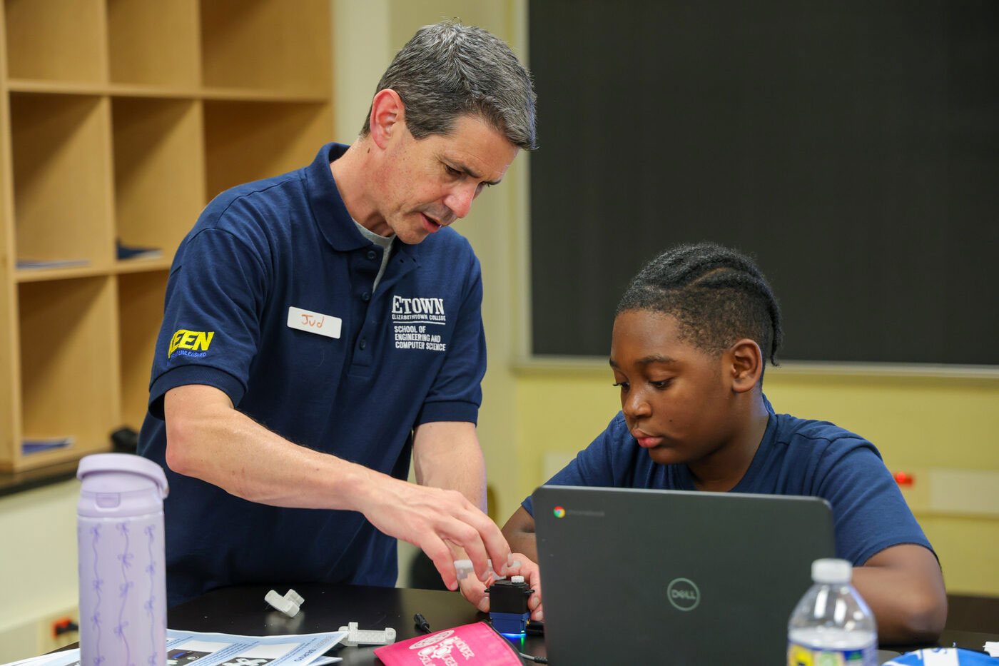 Engineering educator guiding a student during a classroom pilot